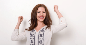 Lady smiling wide with both hands in the air