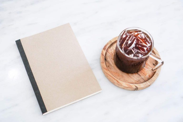 Notebook beside an iced drink