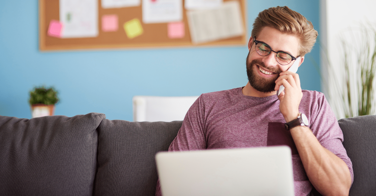 Young guy on phone looking at laptop demonstrates the benefits of hiring a virtual assistant for your maid service