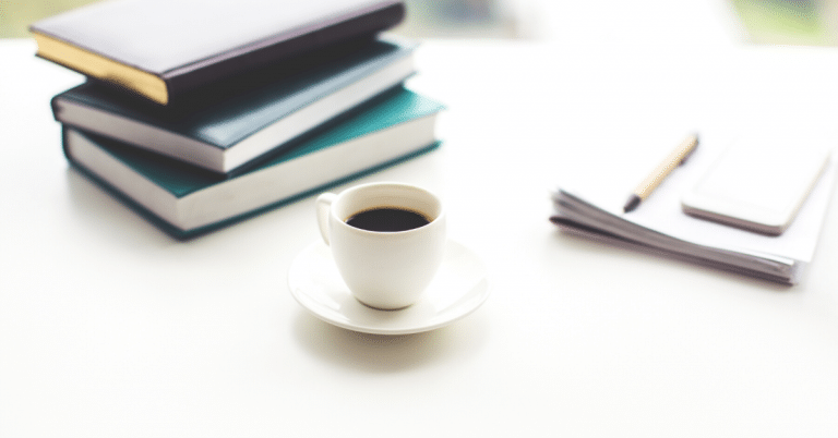 cup of coffee between books and paper