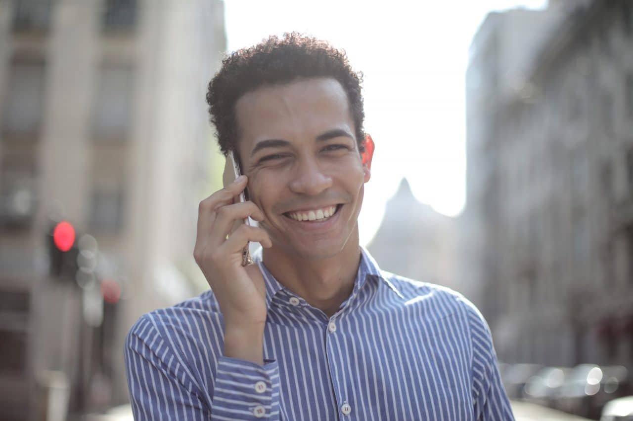 cheerful ethnic man talking on smartphone