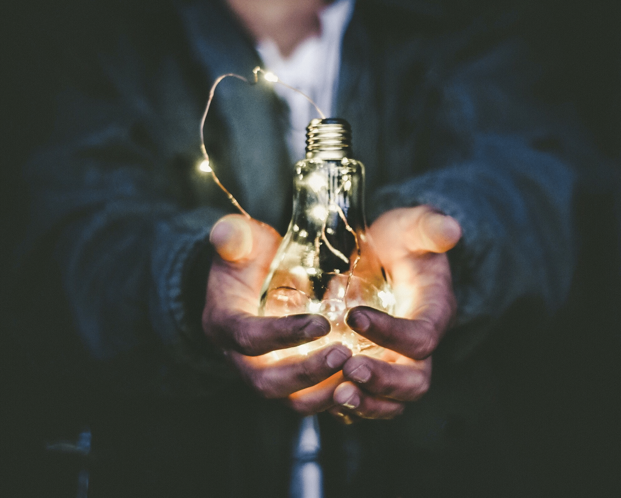 Hands holding out a lightbulb